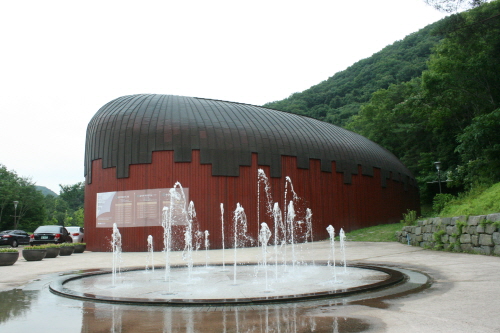 고래모양의 지붕을 하고있는 박물관과 그 앞의 분수대에서 물이 뿜어져 나오고 있다.